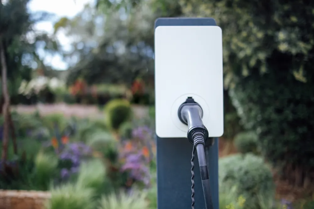 Borne de recharge pour véhicule électrique installée dans un jardin.