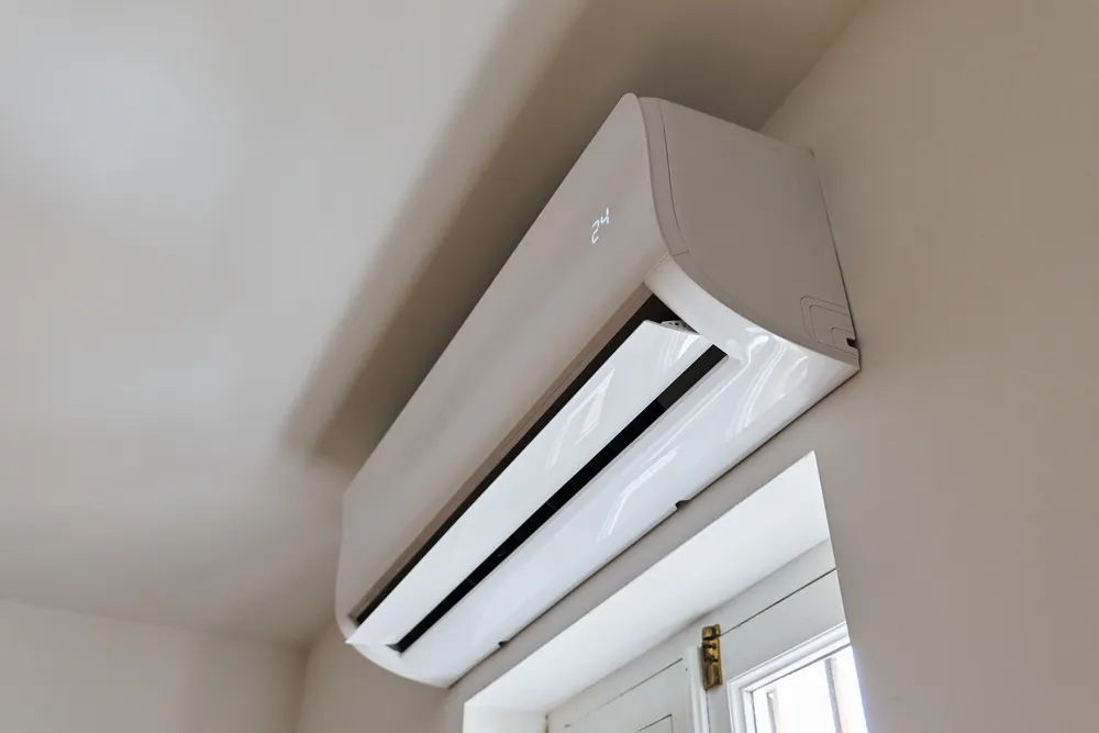 Unité intérieure de climatisation murale installée au-dessus d'une fenêtre.