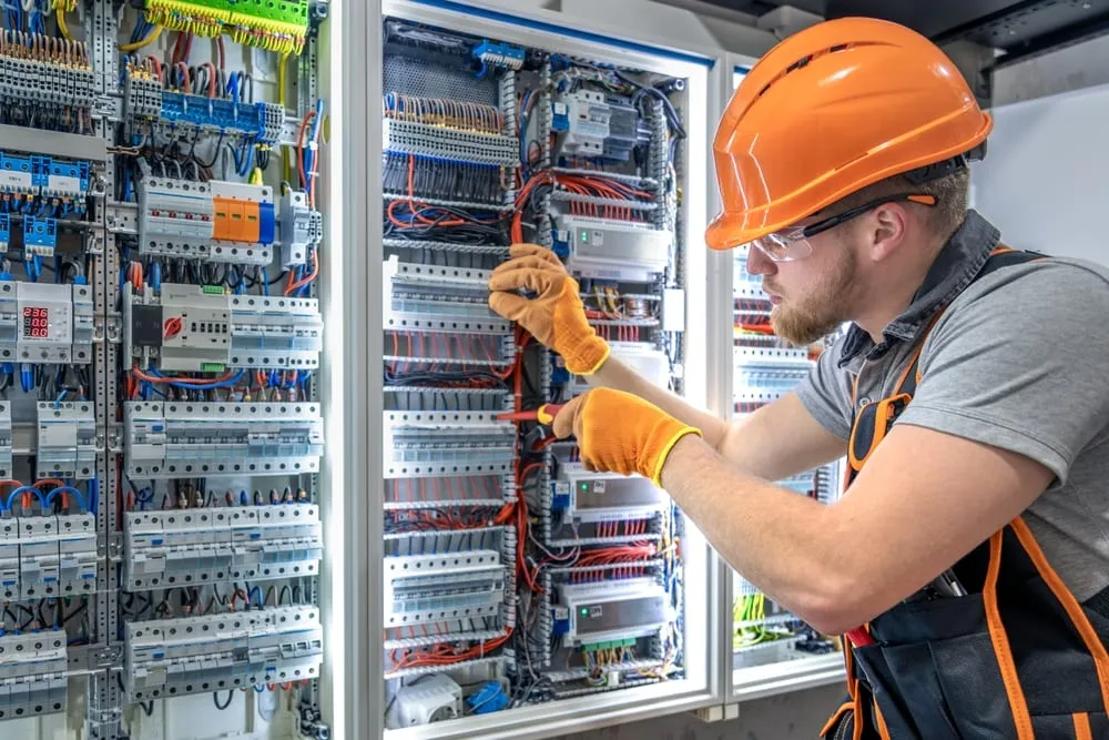Électricien intervenant sur le câblage d'une armoire électrique industrielle.